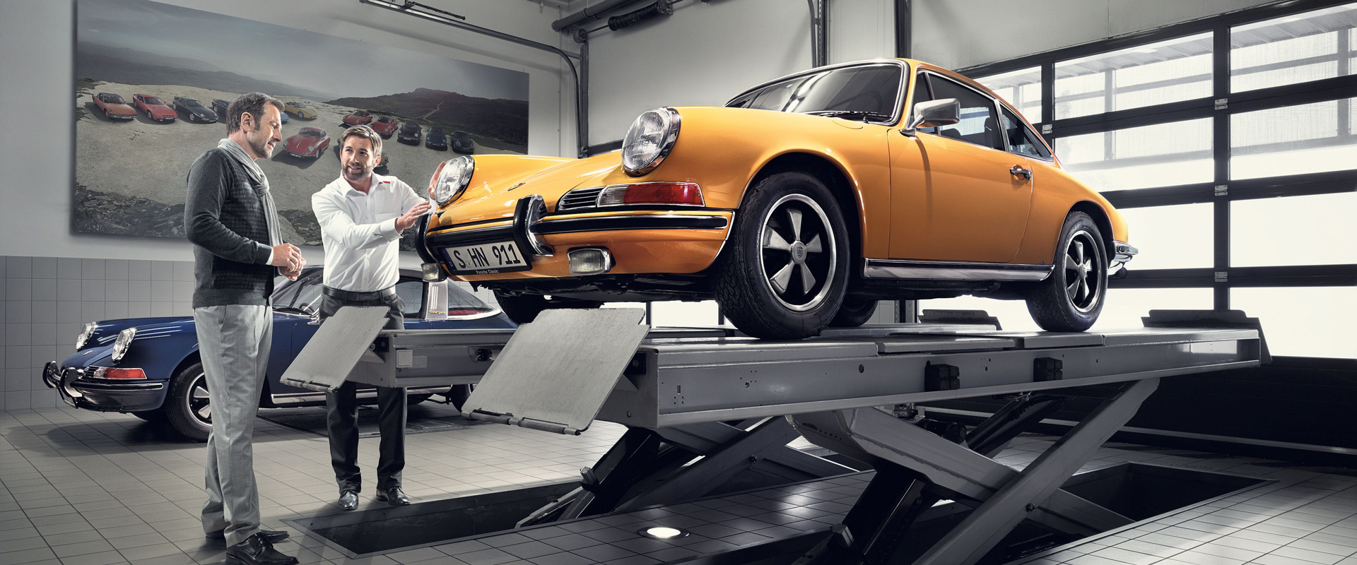 orange porsche on hoist